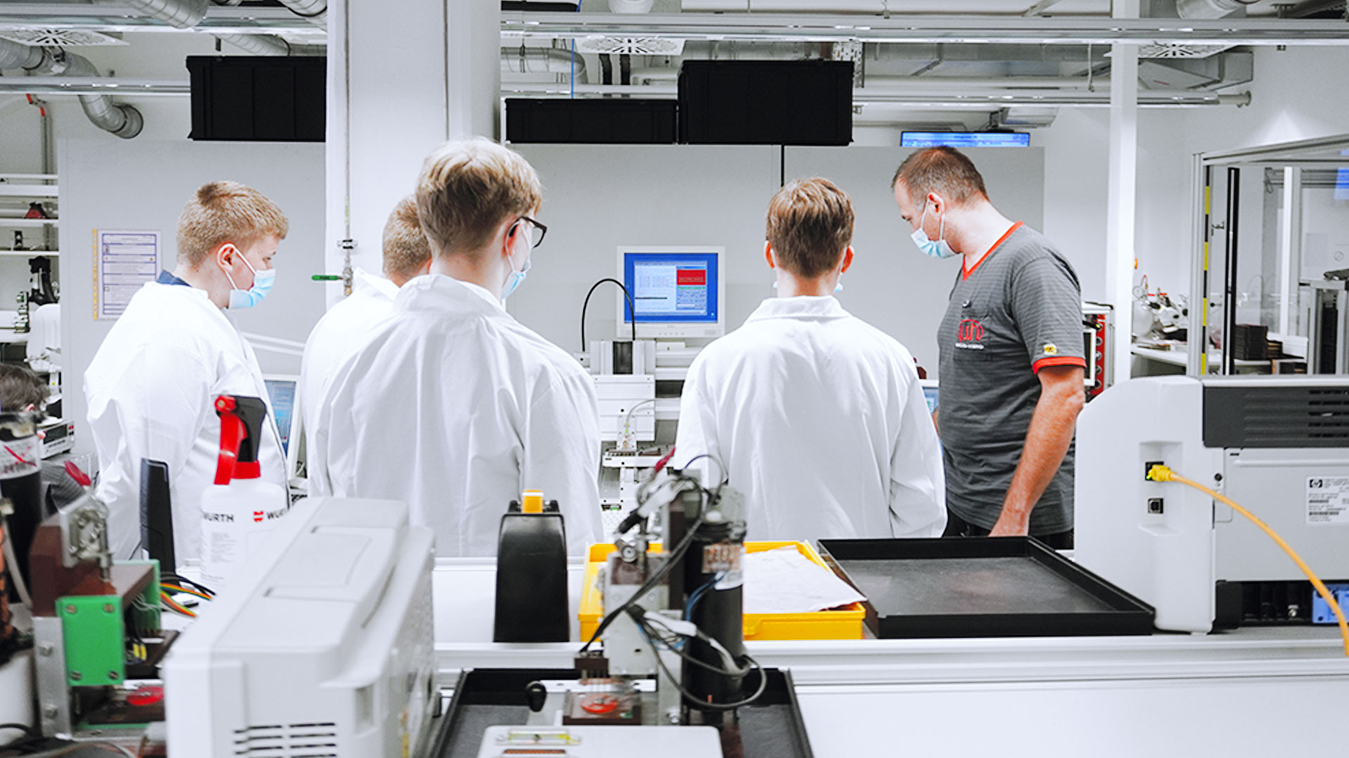 Vier Auszubildenden und ein Ausbilder vom Unternehmen Mitcrohybrid in der Lehrwerkstatt.