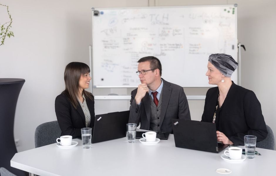 Drei CAMPUS Mitarbeitende unterhalten sich an einem Konferenztisch